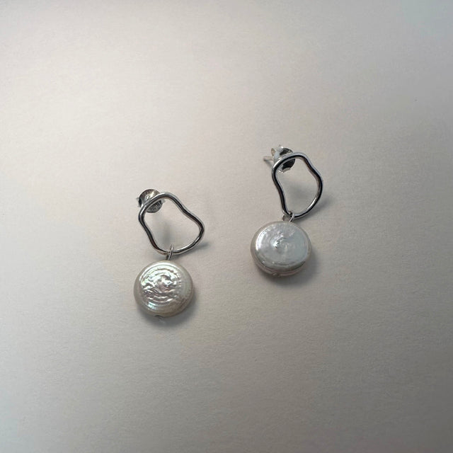 A pair of delicate sterling silver and freshwater pearl earrings, exuding elegance and grace